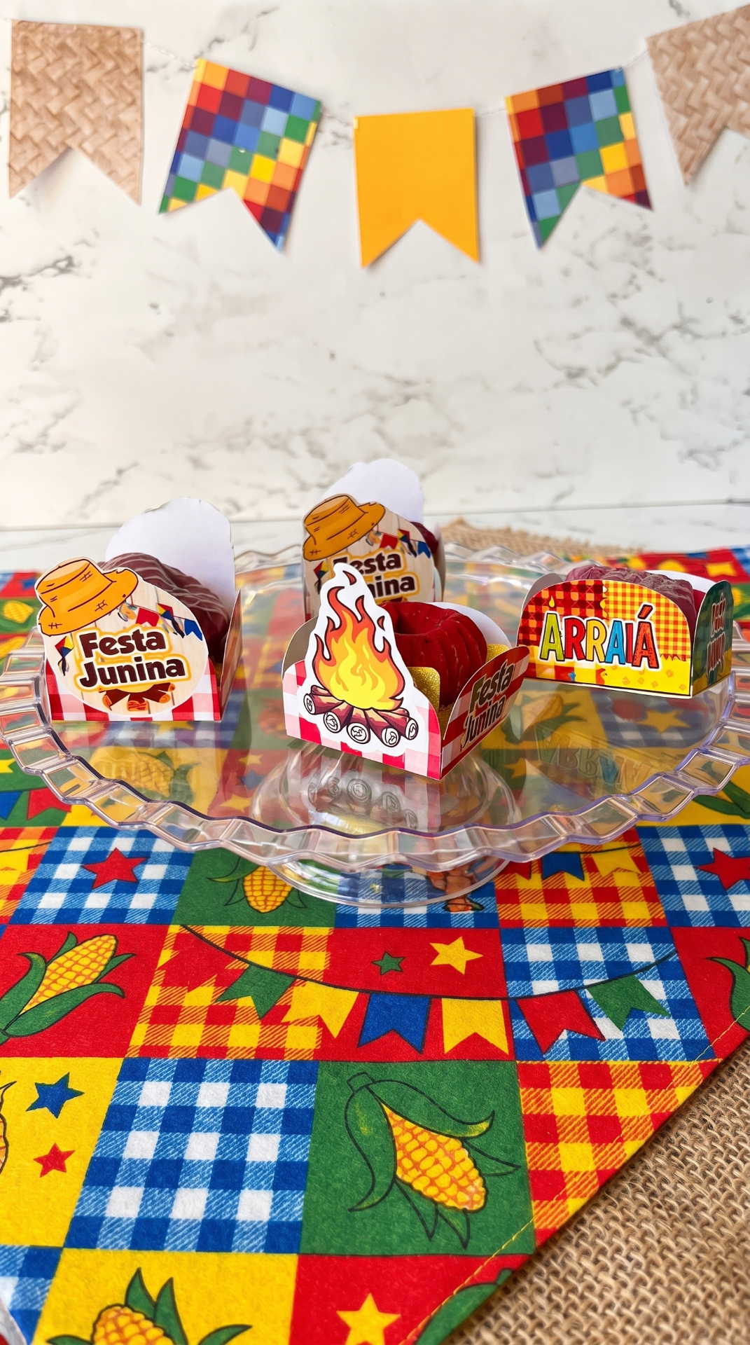 Porta-doces e embalagens juninas montadas sobre prato de vidro